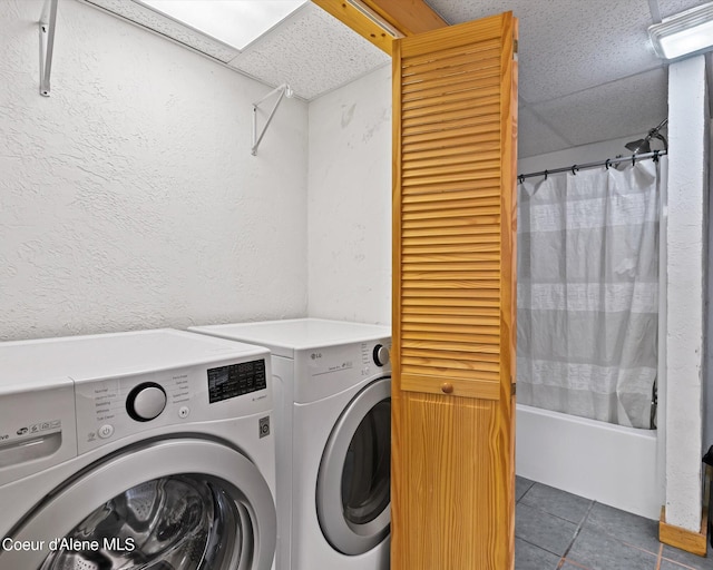 clothes washing area featuring dark tile patterned floors and washing machine and dryer