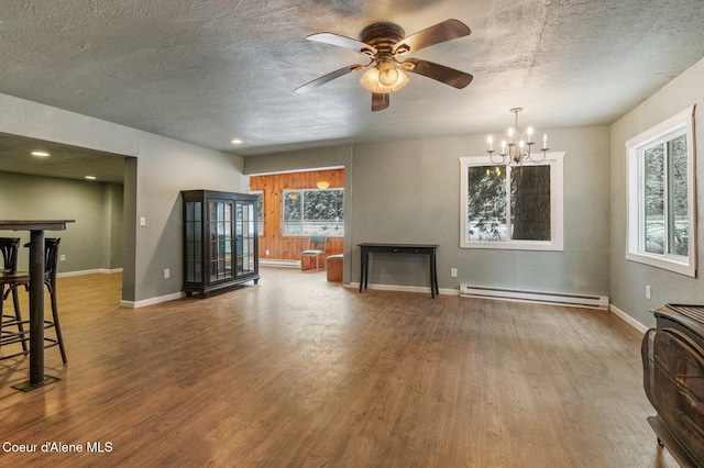 unfurnished living room with a baseboard heating unit, wood-type flooring, a textured ceiling, and plenty of natural light