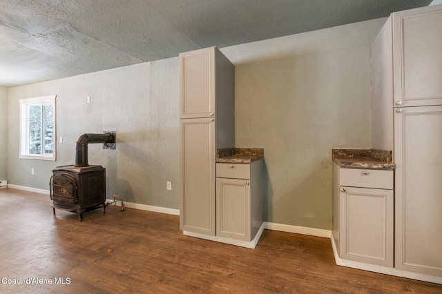 interior space with a wood stove, hardwood / wood-style floors, and white cabinets