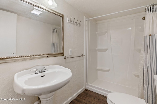 bathroom featuring wood-type flooring, sink, curtained shower, and toilet