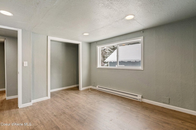 unfurnished bedroom featuring hardwood / wood-style flooring, a baseboard radiator, a textured ceiling, and a closet