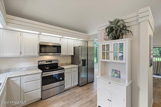 kitchen with light stone counters, light hardwood / wood-style flooring, stainless steel appliances, and white cabinets