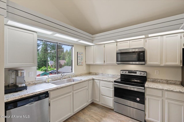 kitchen featuring lofted ceiling, sink, white cabinets, light hardwood / wood-style floors, and stainless steel appliances