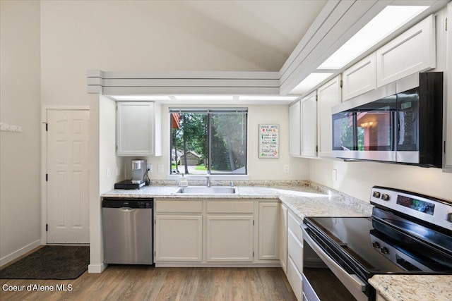 kitchen with lofted ceiling, stainless steel appliances, sink, and white cabinets