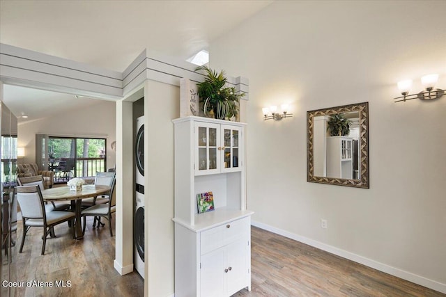 hall with vaulted ceiling, stacked washer / drying machine, and hardwood / wood-style floors