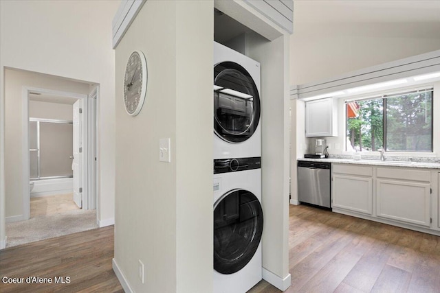 washroom with stacked washer and dryer, sink, and light wood-type flooring