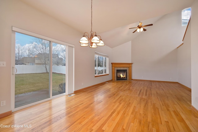 unfurnished living room featuring high vaulted ceiling, a fireplace, light hardwood / wood-style floors, and a chandelier