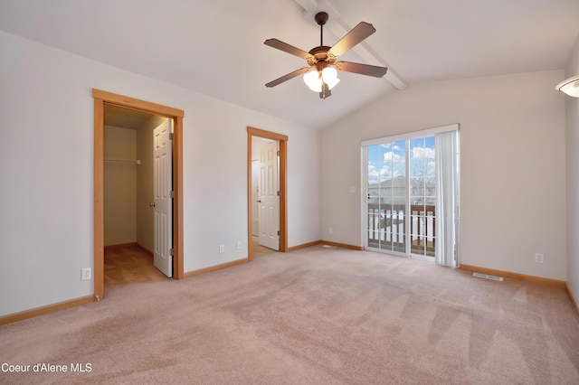 unfurnished bedroom with a walk in closet, vaulted ceiling with beams, light carpet, and access to exterior