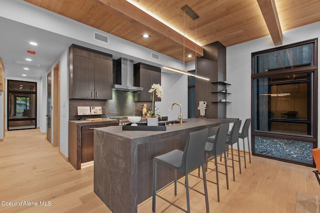 kitchen with tasteful backsplash, wooden ceiling, beamed ceiling, light hardwood / wood-style floors, and wall chimney range hood