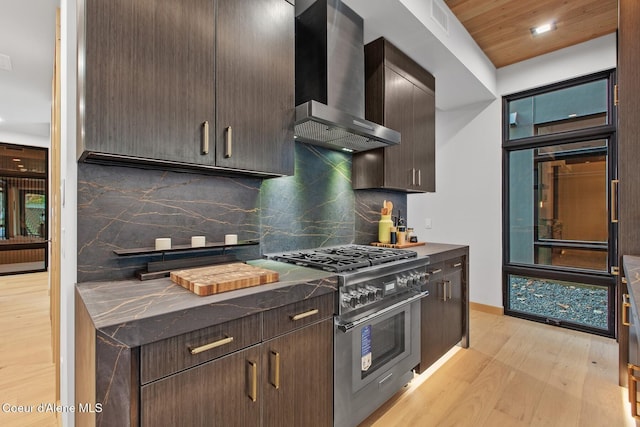 kitchen featuring backsplash, high end stainless steel range, dark brown cabinets, and wall chimney range hood