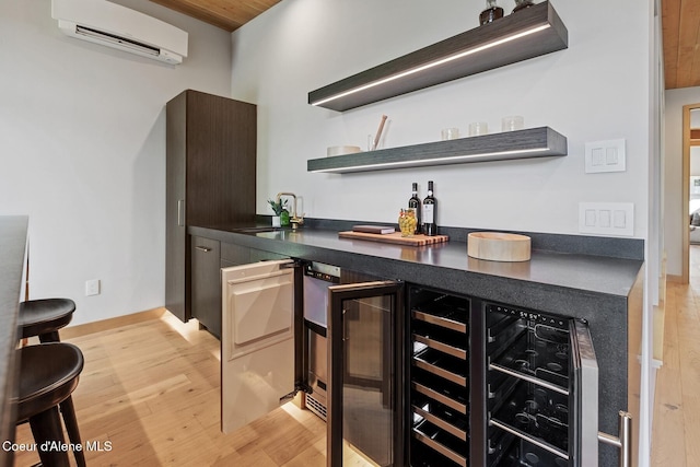 bar featuring sink, a wall mounted AC, and light hardwood / wood-style floors