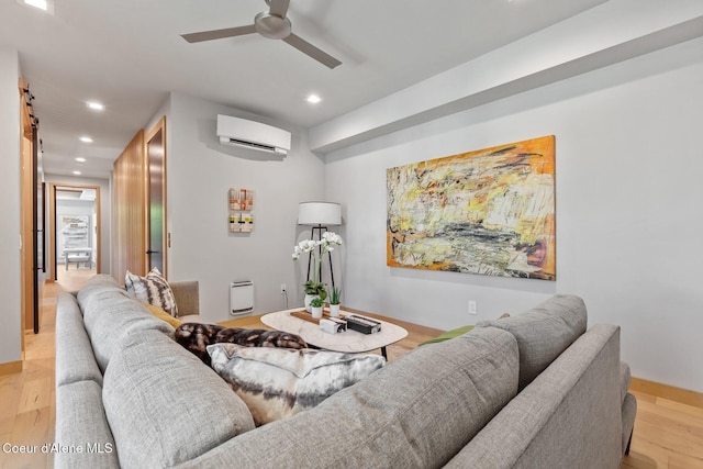 living room with ceiling fan, a wall mounted air conditioner, and light hardwood / wood-style floors