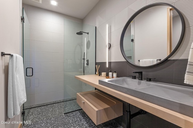 bathroom featuring vanity, decorative backsplash, tile walls, and tiled shower