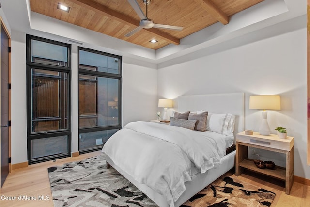 bedroom featuring beamed ceiling, a raised ceiling, wood ceiling, and light hardwood / wood-style flooring