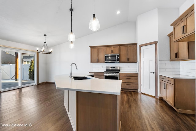 kitchen featuring dark wood-type flooring, sink, appliances with stainless steel finishes, an island with sink, and pendant lighting