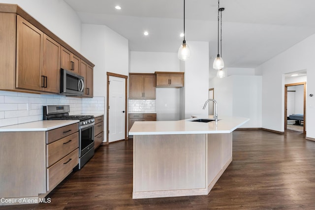 kitchen with sink, hanging light fixtures, dark hardwood / wood-style flooring, stainless steel appliances, and a kitchen island with sink