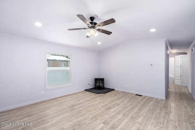 unfurnished living room with crown molding, vaulted ceiling, a wood stove, and light wood-type flooring