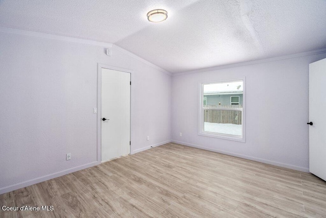 empty room with ornamental molding, light hardwood / wood-style flooring, and a textured ceiling