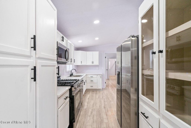 kitchen featuring lofted ceiling, sink, white cabinets, light hardwood / wood-style floors, and stainless steel appliances