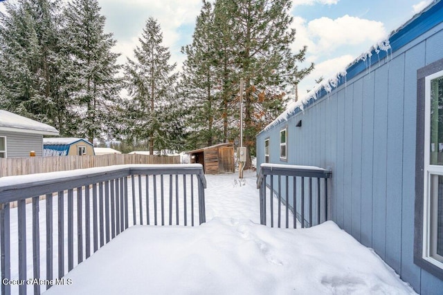 snow covered deck featuring a shed