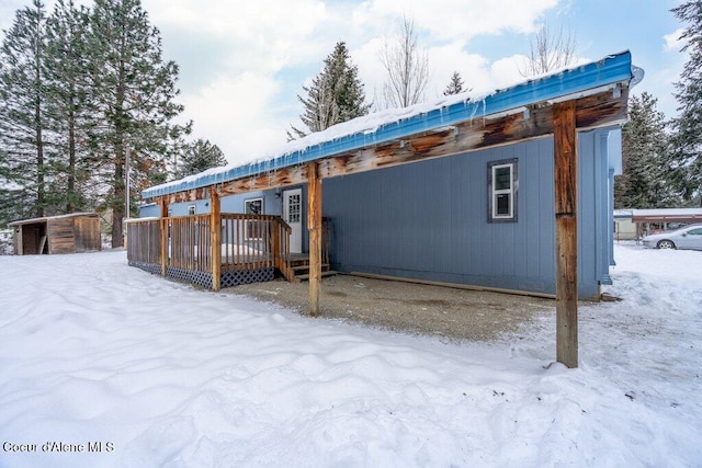 snow covered back of property with a wooden deck