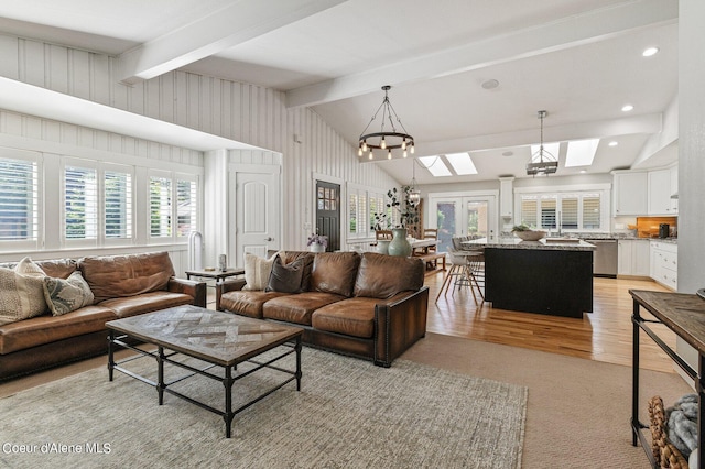 living room featuring sink, light hardwood / wood-style flooring, and vaulted ceiling with skylight