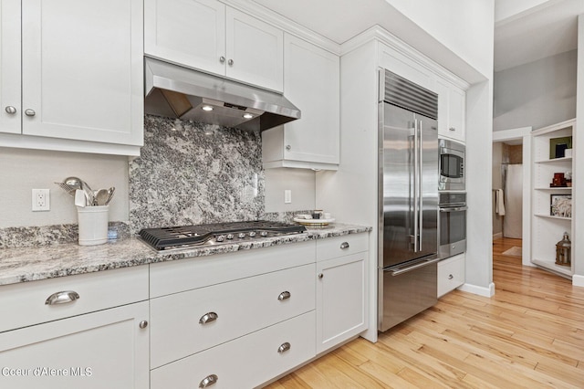 kitchen featuring white cabinetry, built in appliances, light wood-type flooring, and exhaust hood