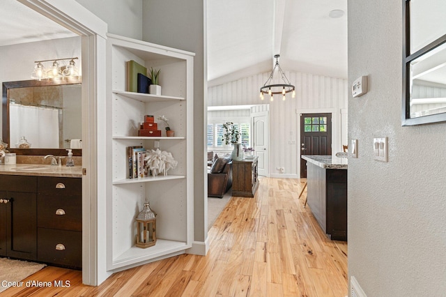 bar featuring hanging light fixtures, dark brown cabinets, sink, and light hardwood / wood-style flooring