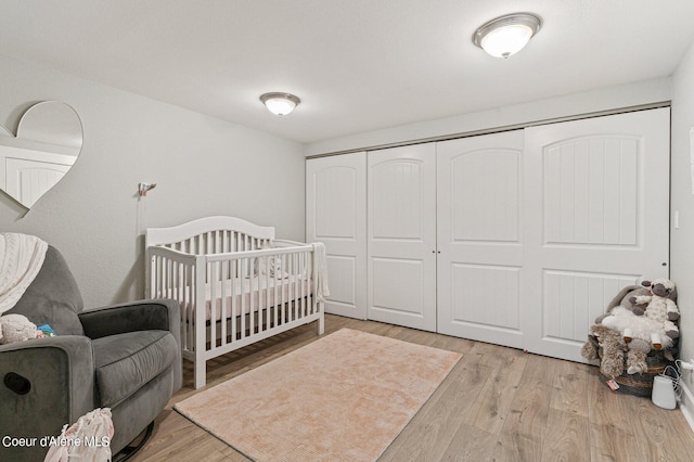 bedroom featuring light hardwood / wood-style flooring, a closet, and a nursery area