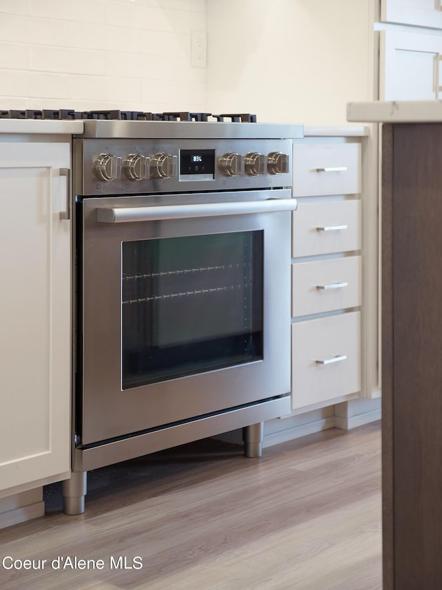 details with light hardwood / wood-style floors, oven, and white cabinets