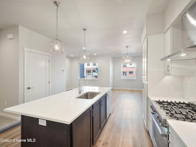 kitchen featuring sink, hanging light fixtures, dark brown cabinetry, stainless steel appliances, and wall chimney exhaust hood