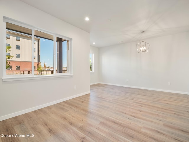 unfurnished room with an inviting chandelier and light hardwood / wood-style floors