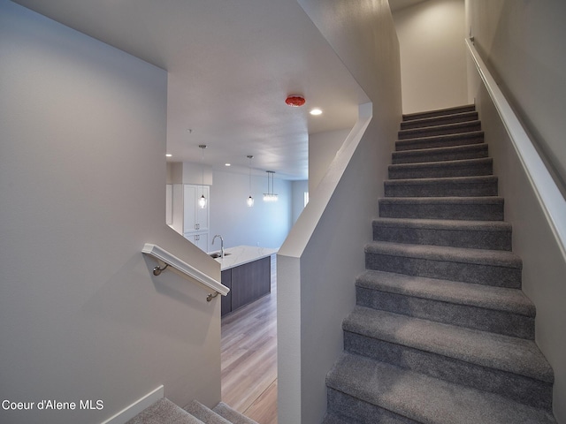 stairs with hardwood / wood-style flooring and sink