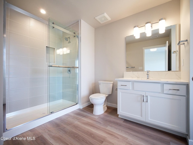 bathroom with hardwood / wood-style flooring, vanity, toilet, and walk in shower