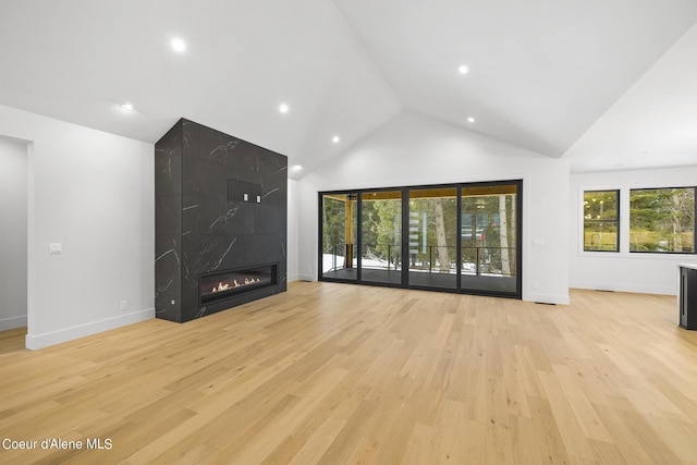 unfurnished living room featuring high vaulted ceiling, a fireplace, and light hardwood / wood-style floors