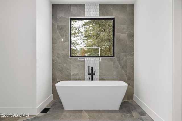 bathroom featuring a washtub and tile walls