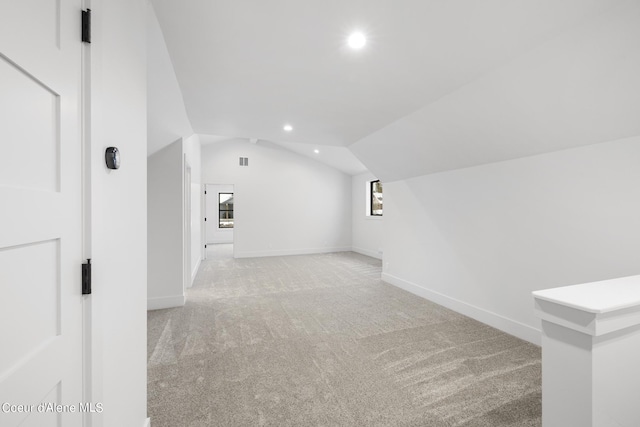 additional living space featuring light colored carpet and vaulted ceiling