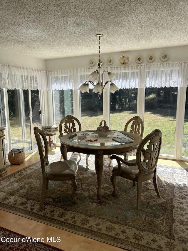 dining area with a textured ceiling, a chandelier, and hardwood / wood-style flooring