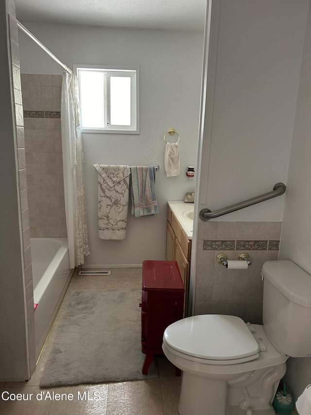 full bathroom with tile walls, vanity, toilet, tile patterned floors, and shower / bath combo with shower curtain