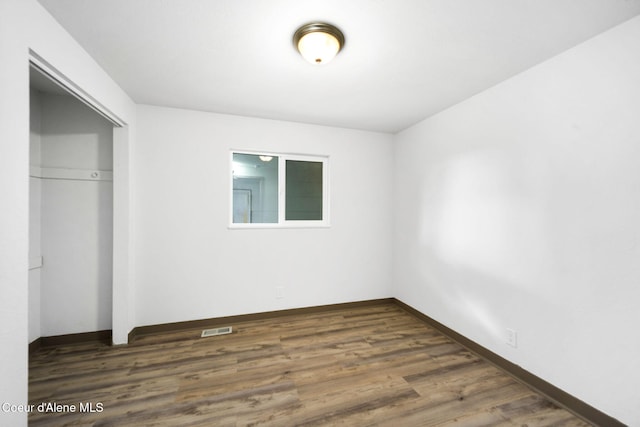 unfurnished bedroom with dark hardwood / wood-style floors and a closet