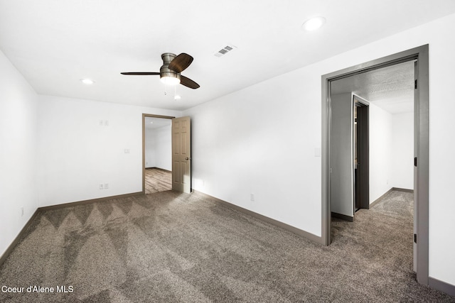 spare room featuring ceiling fan and dark carpet