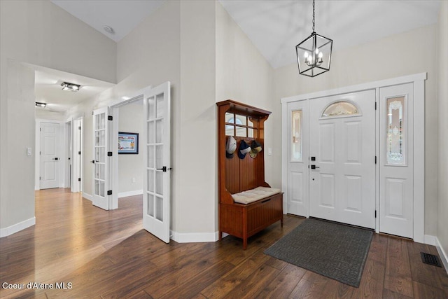 entrance foyer with vaulted ceiling, dark hardwood / wood-style floors, a notable chandelier, and french doors