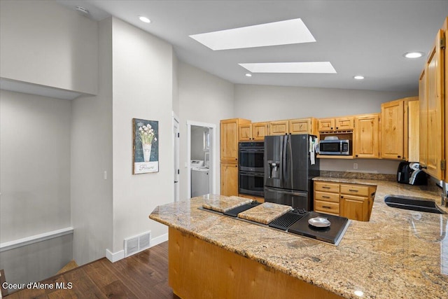 kitchen with kitchen peninsula, sink, light stone countertops, and black appliances