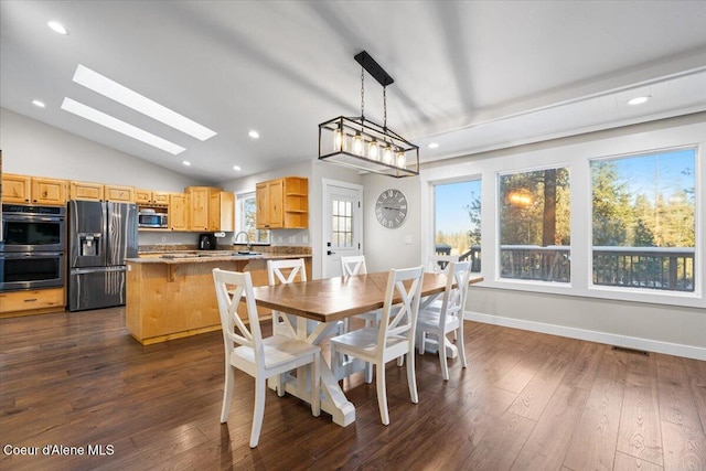 dining space with plenty of natural light, dark hardwood / wood-style flooring, and lofted ceiling with skylight