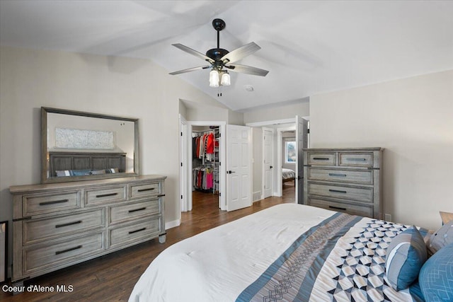 bedroom featuring dark wood-type flooring, a spacious closet, vaulted ceiling, a closet, and ceiling fan