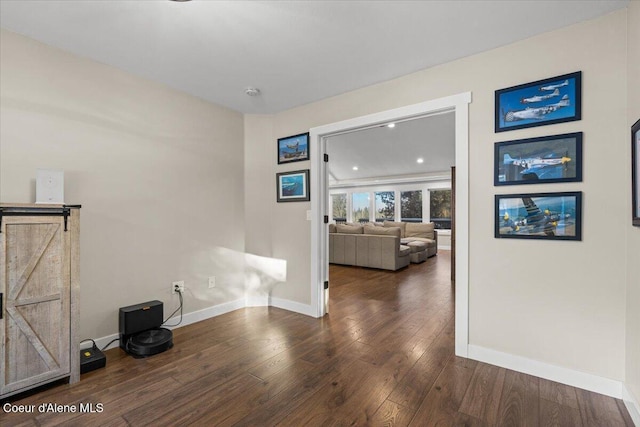 unfurnished room with a barn door and dark hardwood / wood-style flooring