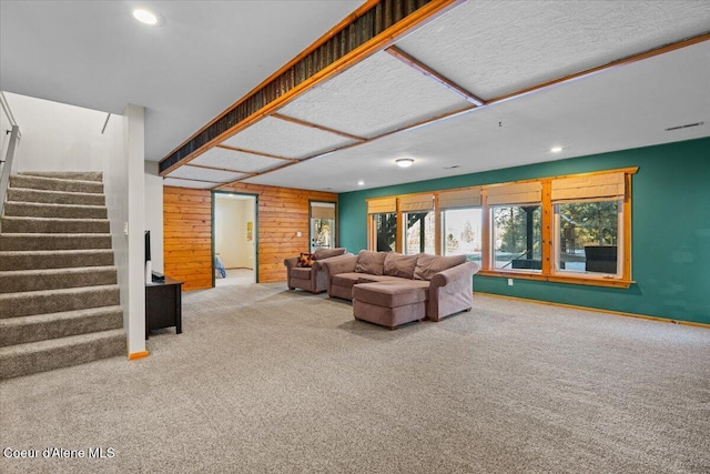 carpeted living room featuring wooden walls