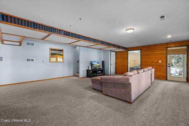 carpeted living room with wood walls