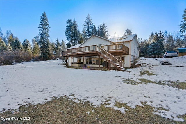 snow covered back of property featuring a deck