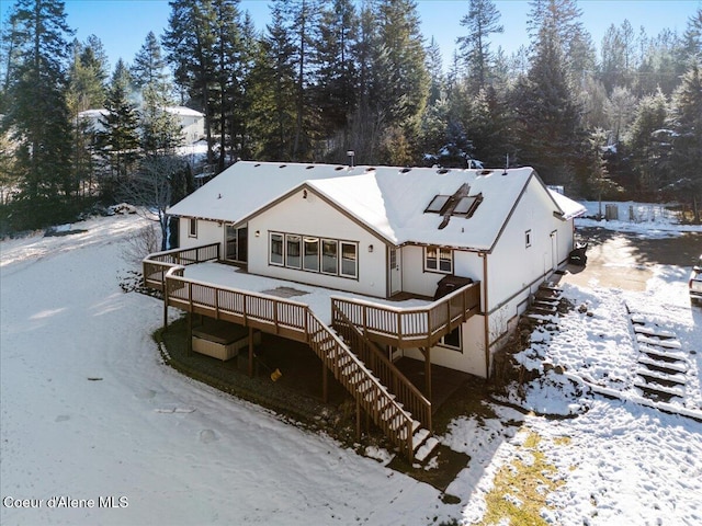 snow covered rear of property with a wooden deck